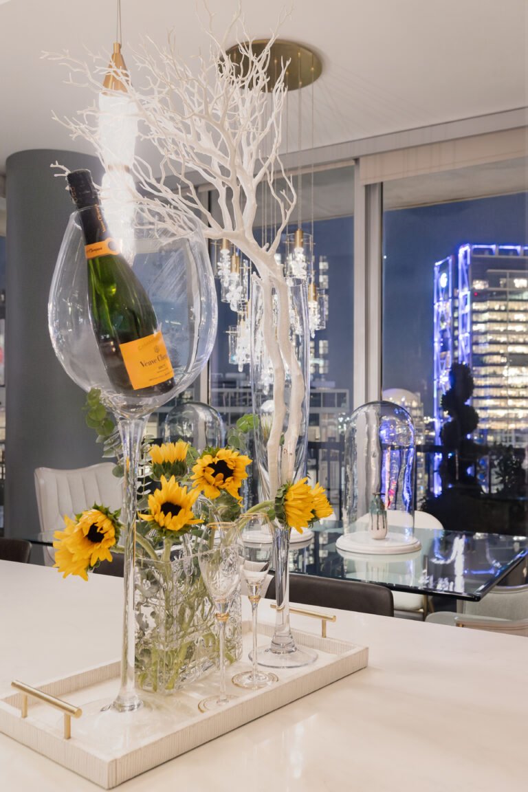Champagne and sunflowers on a white counter with city lights behind