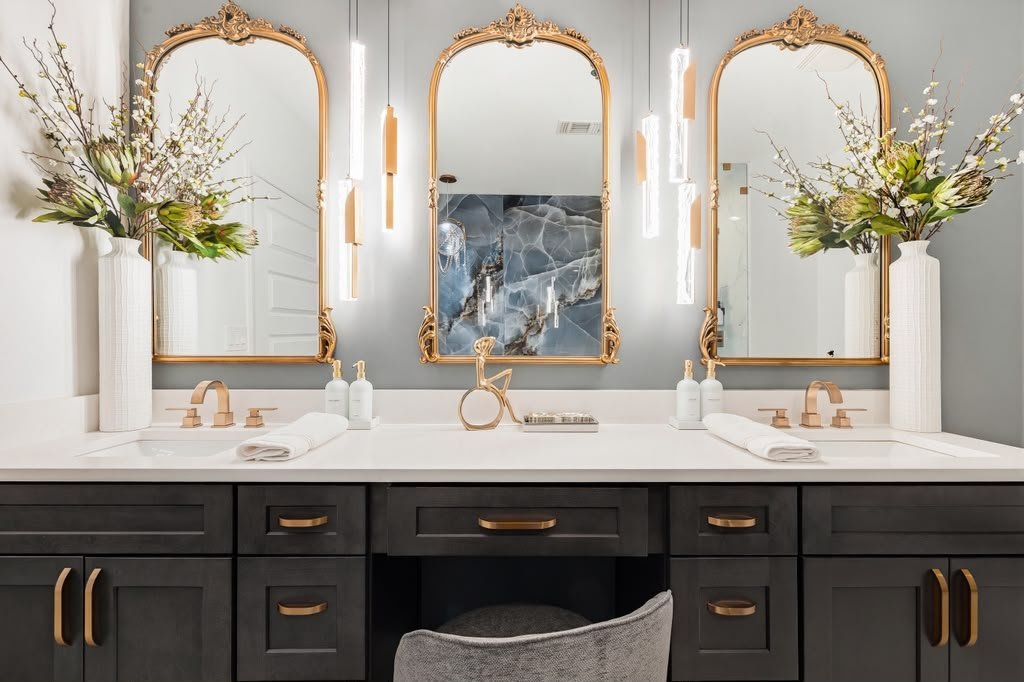 Double vanity with three gilt arched mirrors and dark cabinetry