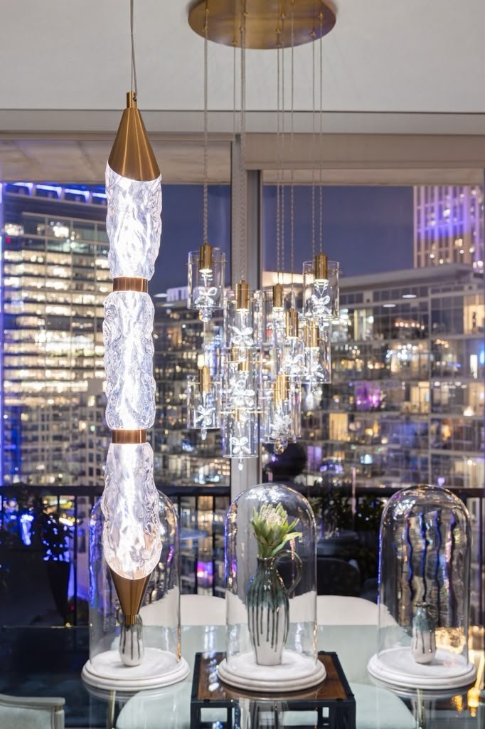 Dining table with glass cloches under brass pendants