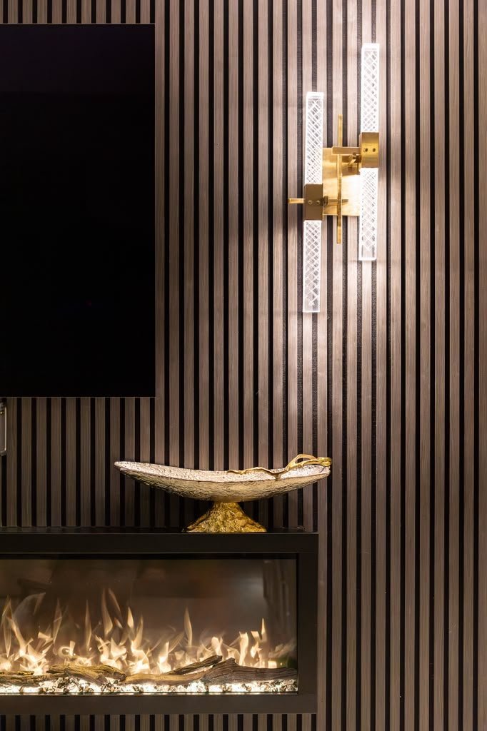 Brass sconce, gilt bowl and fireplace flame on a fluted wall