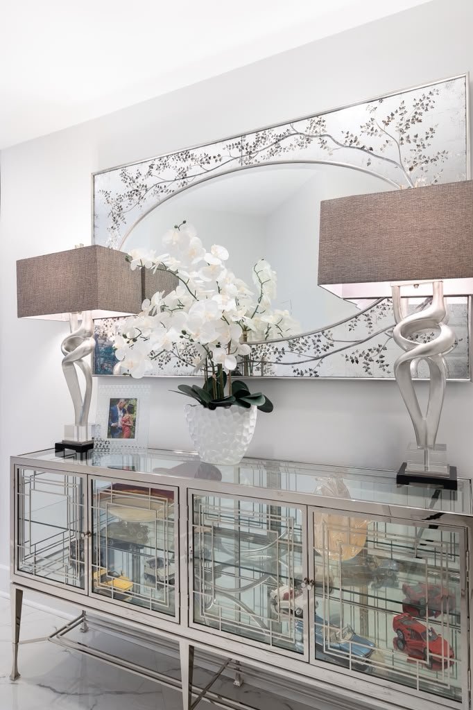 Mirrored console with an orchid between two lamps