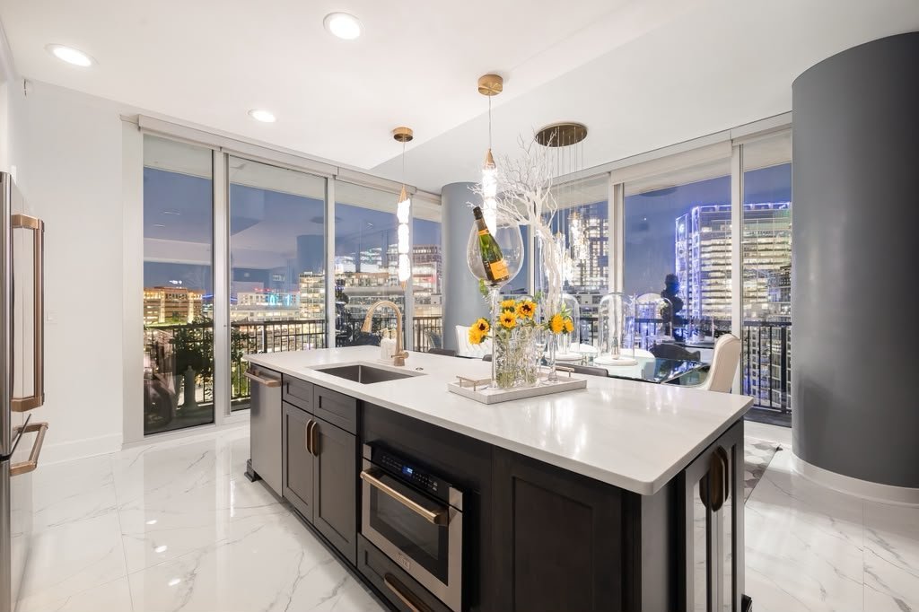 Kitchen with a dark island on white marble floors