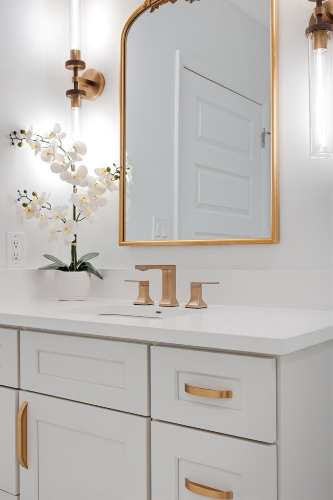 Powder room vanity with an orchid, brass tap and pale wood